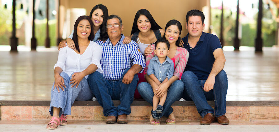 Multigenerational Latin family smiles with a child, teens, young adults, parents, and grandpa