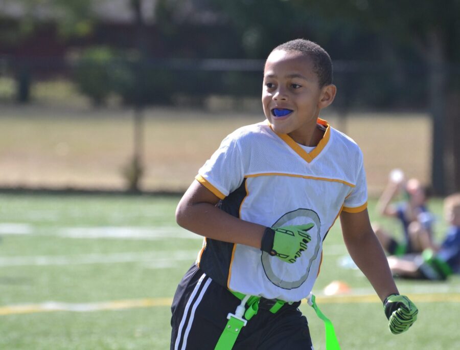 A boy playing flag football while wearing a sports mouthguard to protect his teeth