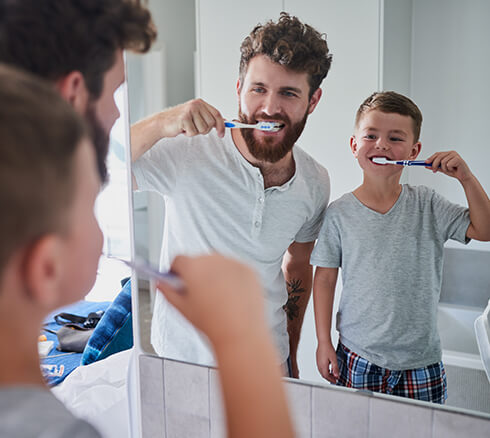 father and son brushing their teeth together