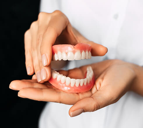 person holding a set of dentures