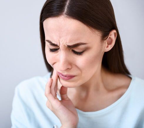 woman holding her jaw in pain