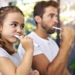 family dentist vs general dentist,dad and daughter brushing their teeth