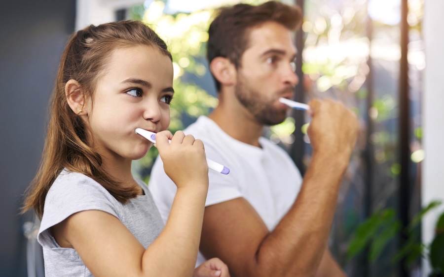 family dentist vs general dentist,dad and daughter brushing their teeth